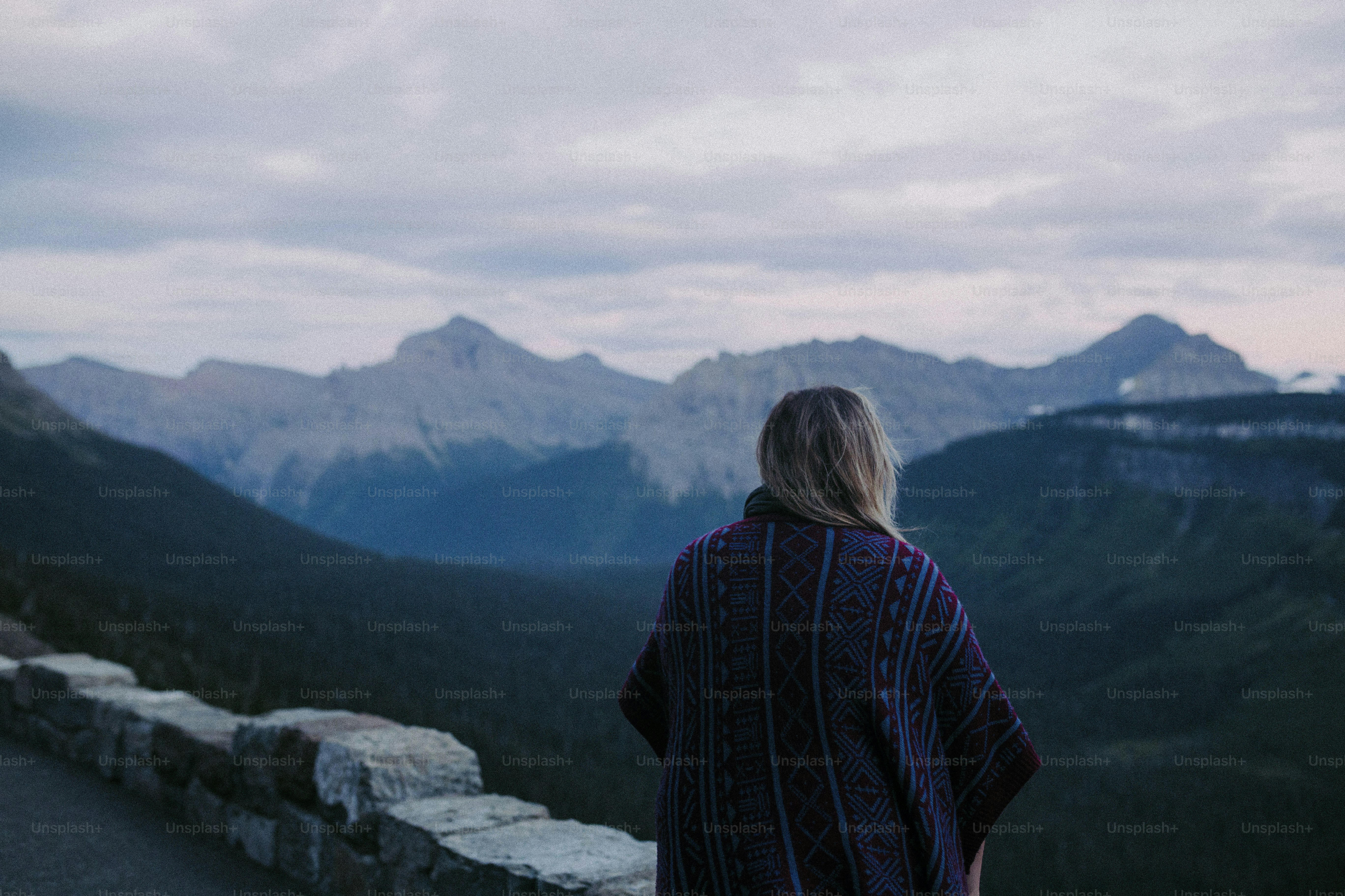 a woman standing on top of a mountain overlooking a valley