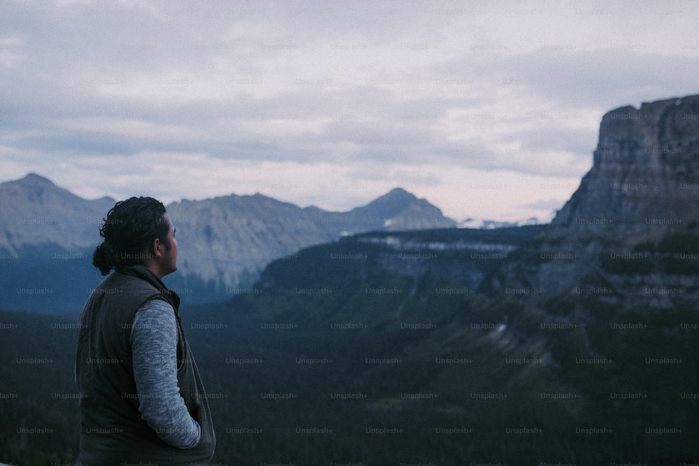 Un hombre parado en la cima de una montaña con vistas a un valle