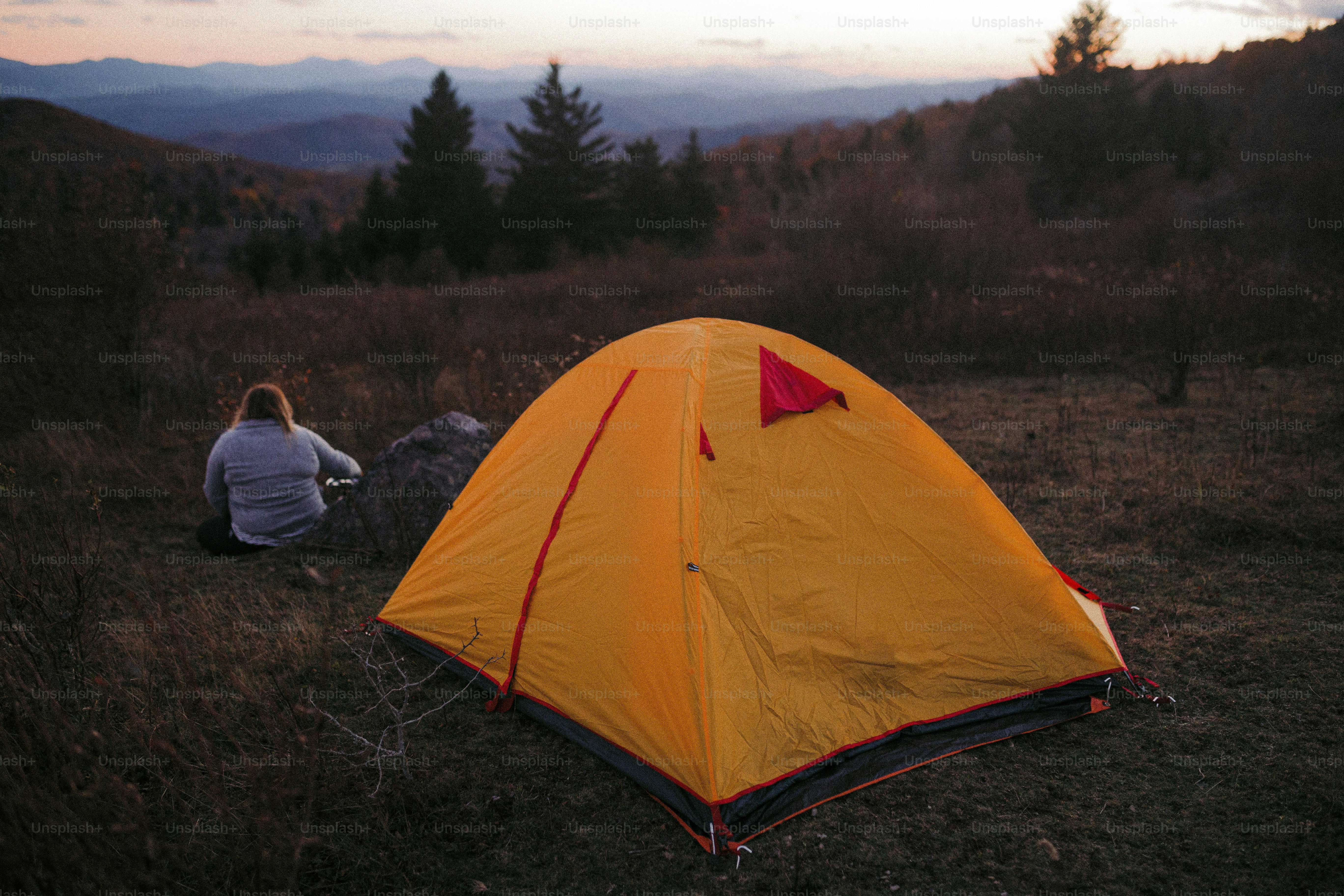 a person sitting in a field next to a tent