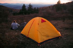 uma pessoa sentada em um campo ao lado de uma tenda