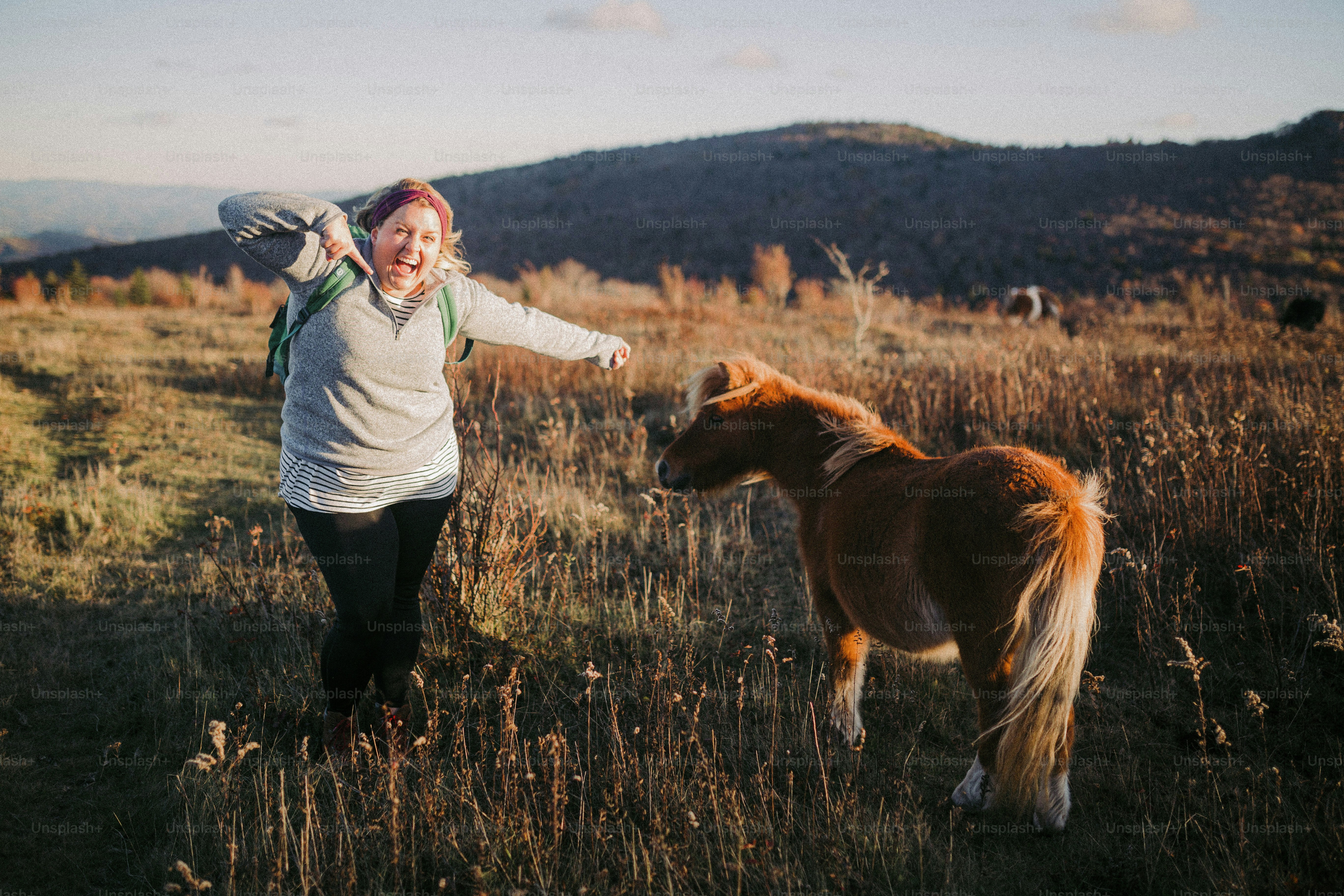 a woman is walking with a pony in a field
