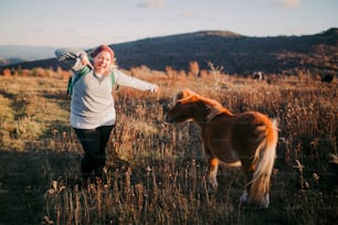 Una mujer camina con un pony en un campo