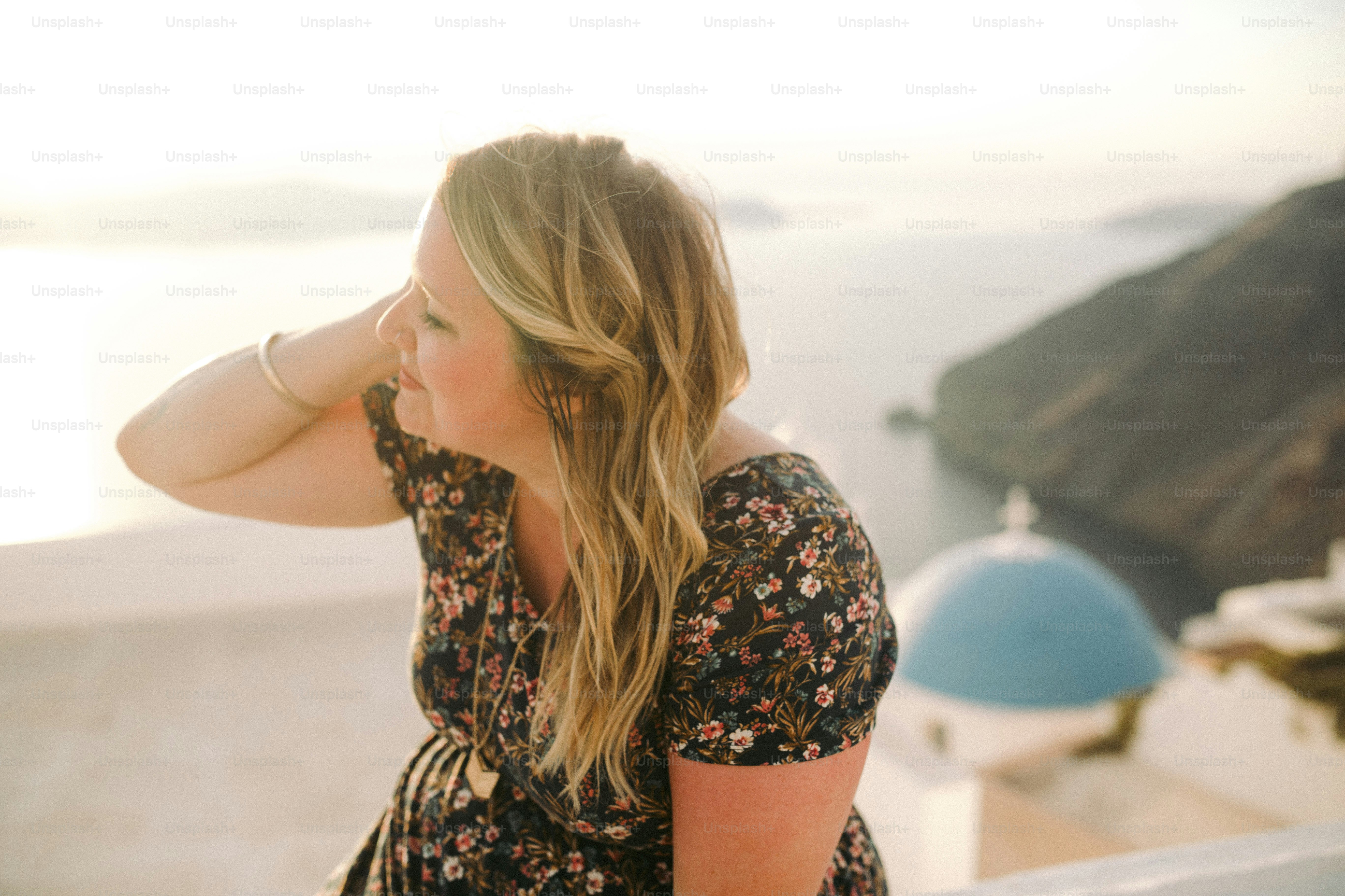 Una donna seduta su una sporgenza che guarda l'oceano