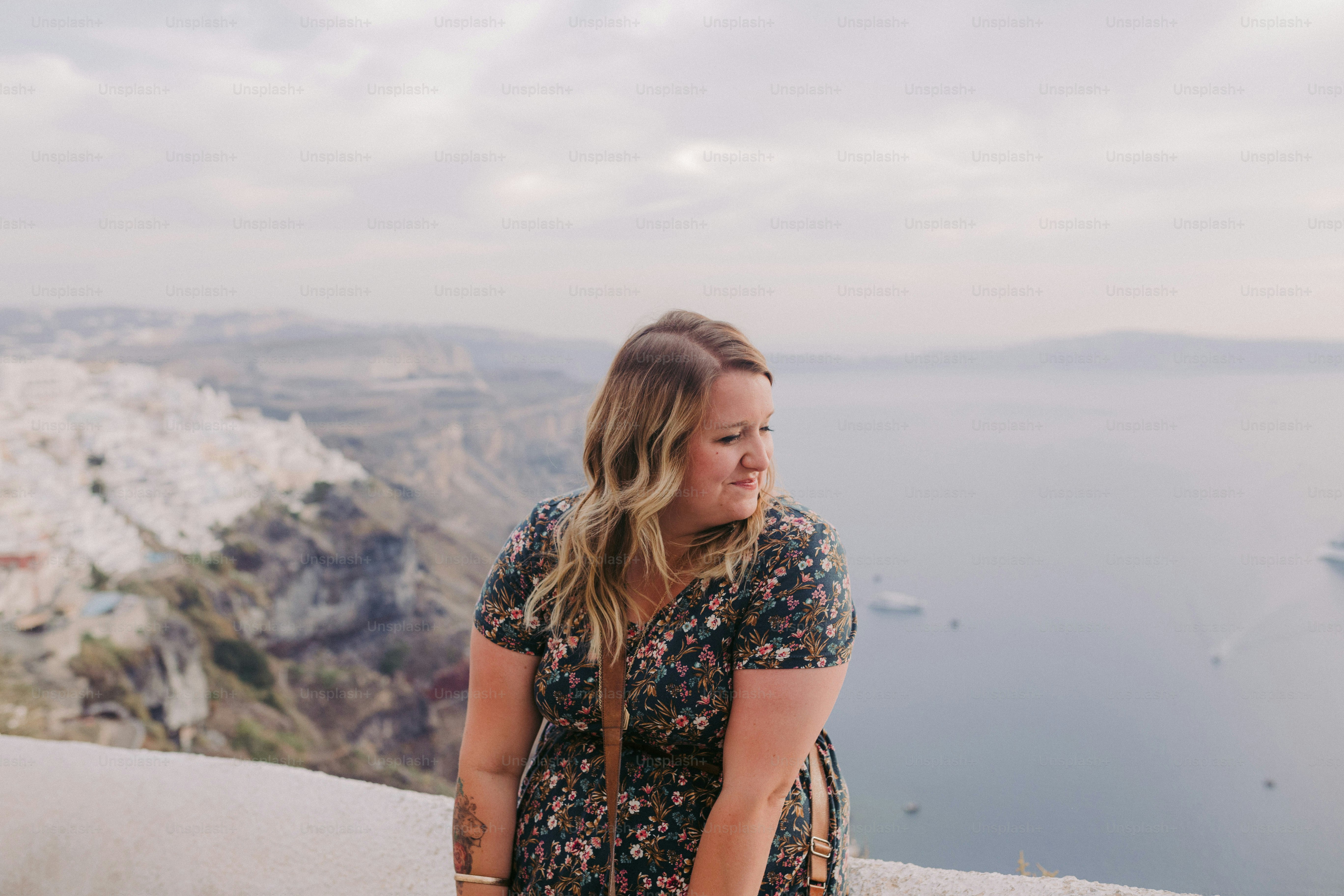 a woman standing on top of a hill next to a body of water