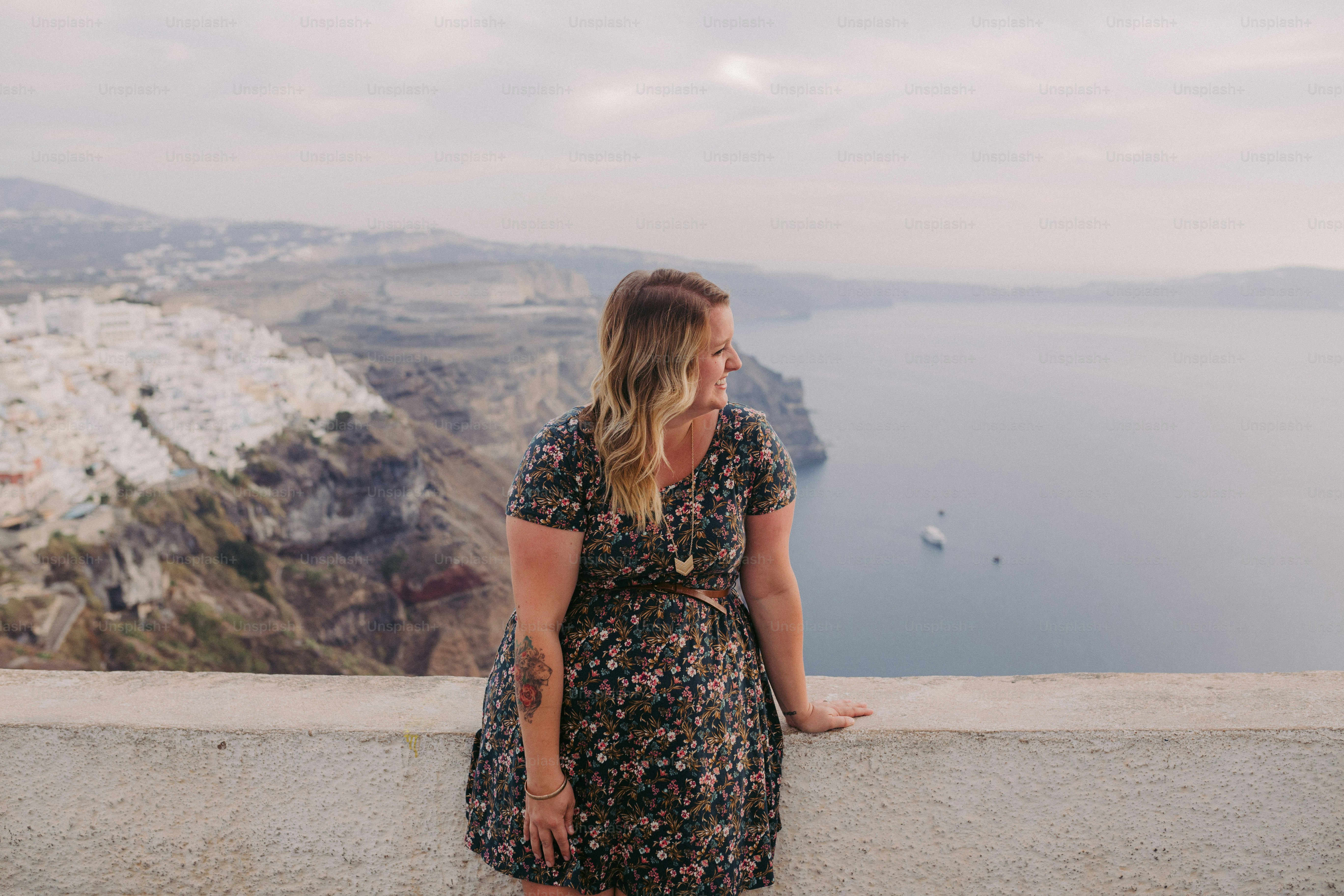 a woman standing on a ledge overlooking a body of water