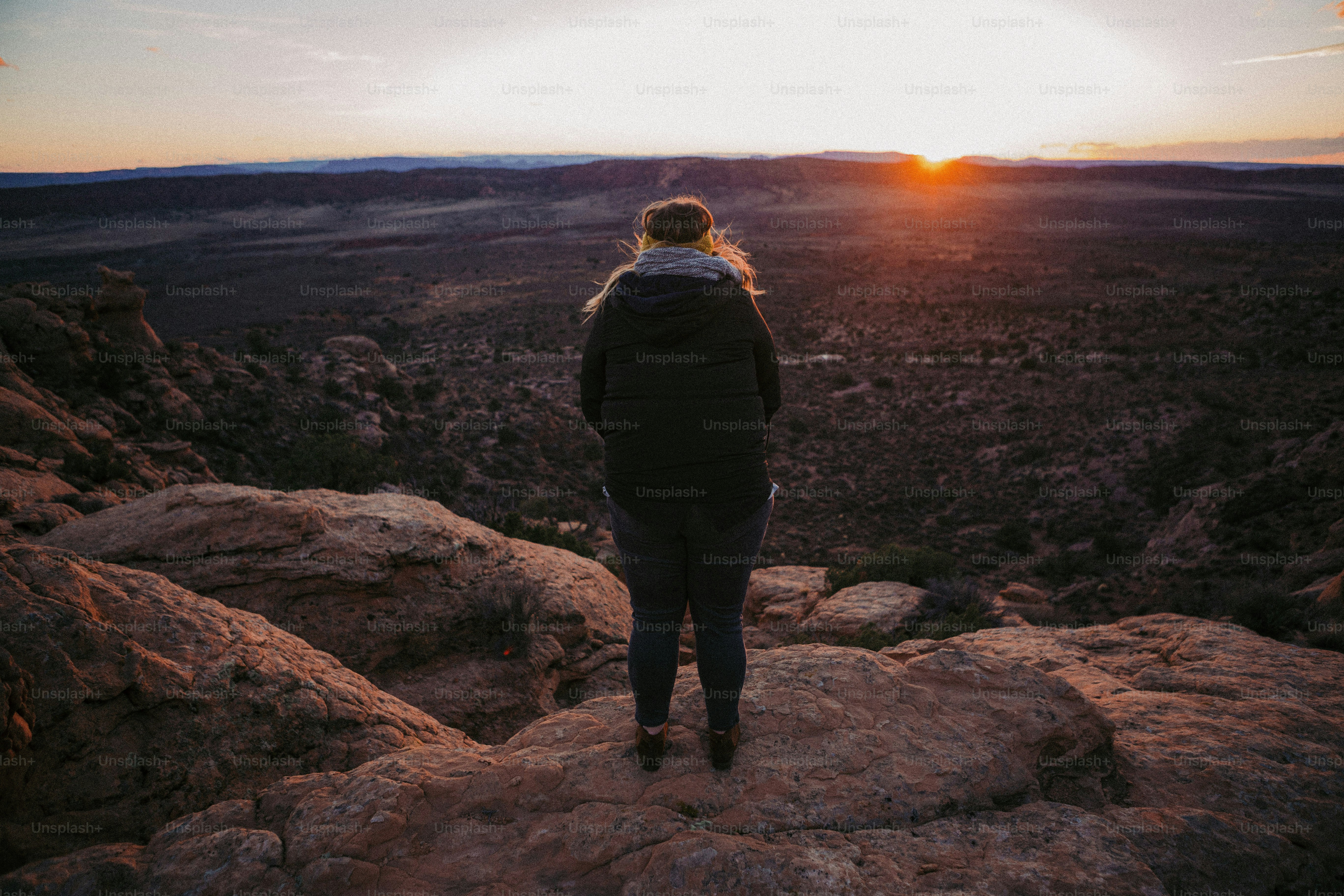 una donna in piedi sulla cima di una grande roccia