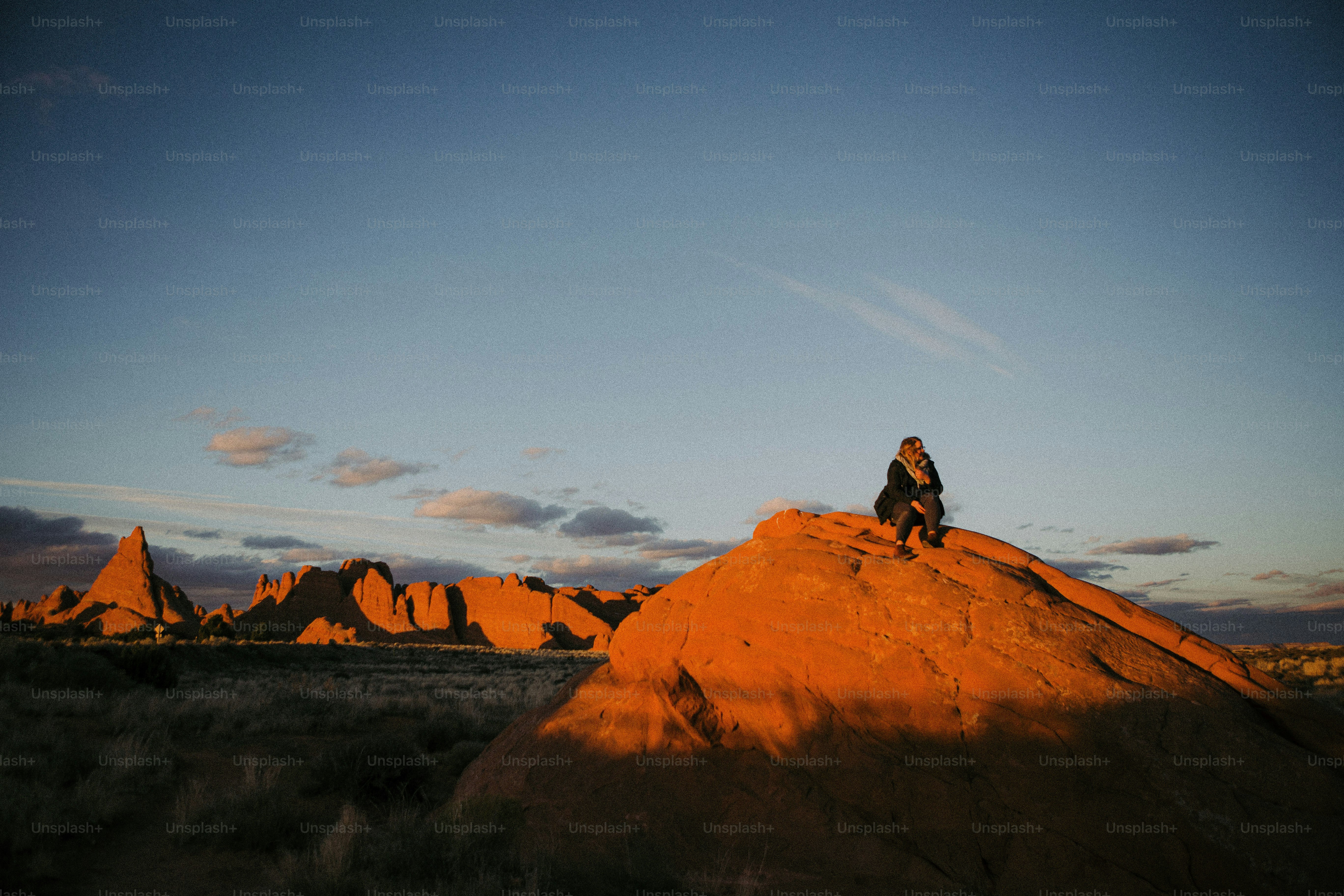 a man sitting on top of a large rock