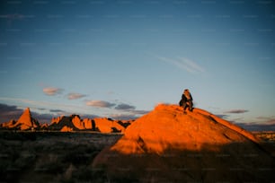 Un uomo seduto sulla cima di una grande roccia