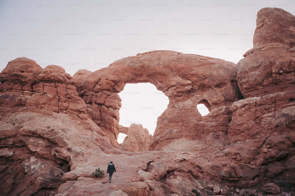 uma pessoa em pé em uma área rochosa com um buraco na rocha