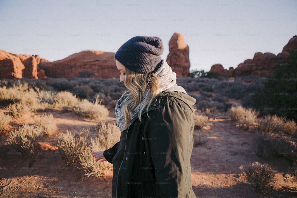 a woman standing in the desert with a hat on