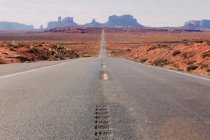 a long straight road with mountains in the background