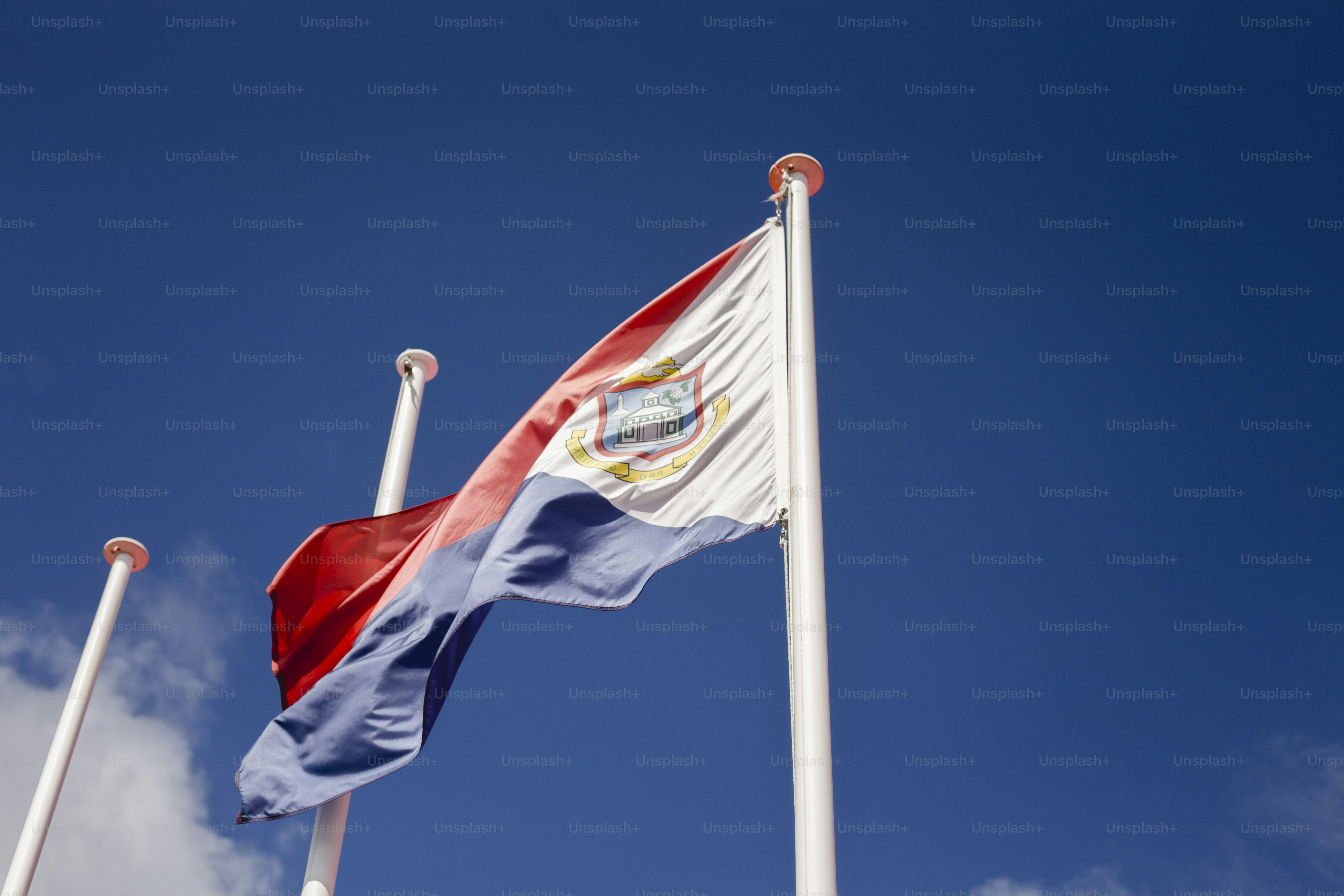 two flags flying in the wind with a blue sky in the background