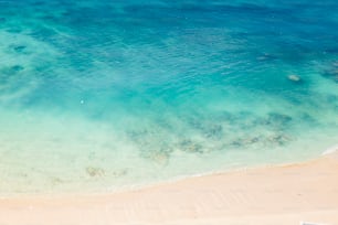 an aerial view of a sandy beach with clear blue water