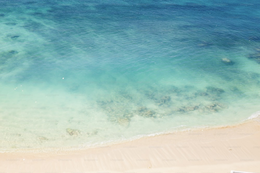 an aerial view of a sandy beach with clear blue water