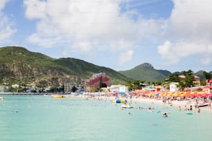 a crowded beach with a mountain in the background