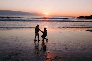 a couple of people standing on top of a beach