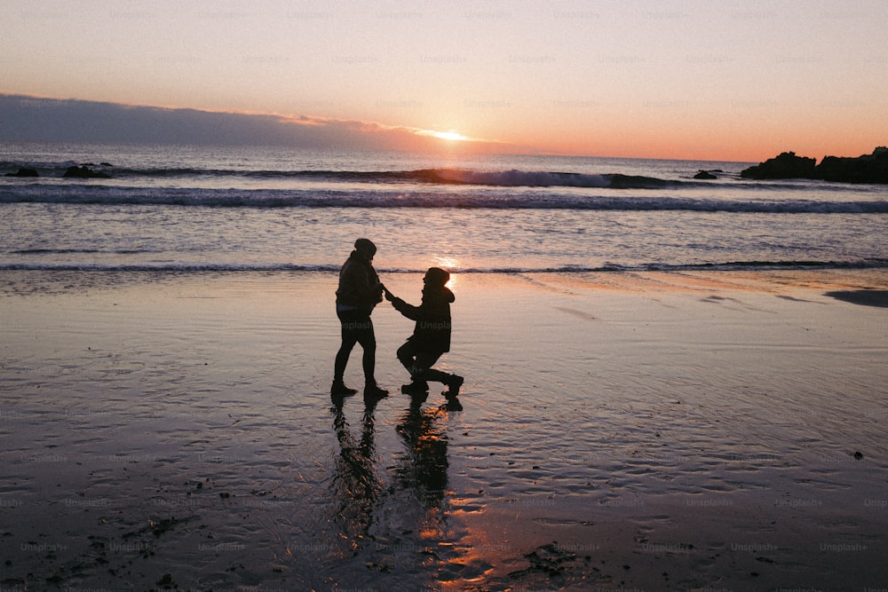 a couple of people standing on top of a beach