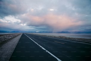 an empty highway with a cloudy sky in the background