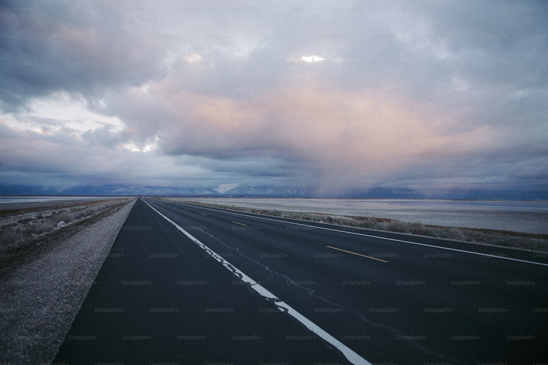 an empty highway with a cloudy sky in the background