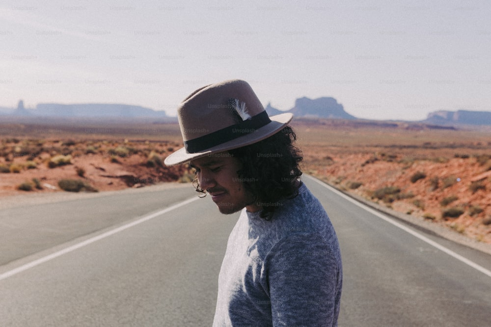 a man with a hat is standing on the side of the road