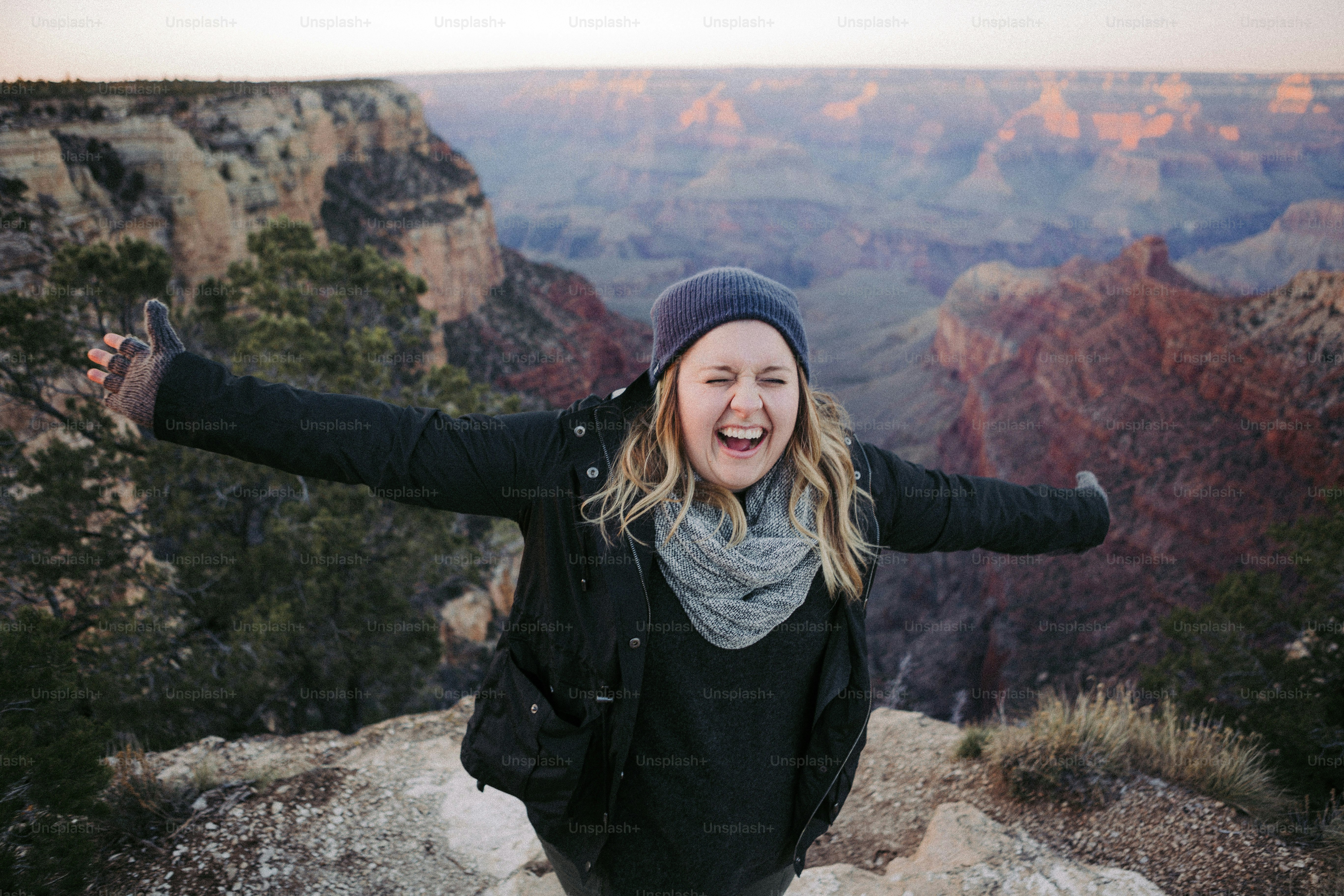 a woman standing on top of a mountain with her arms outstretched
