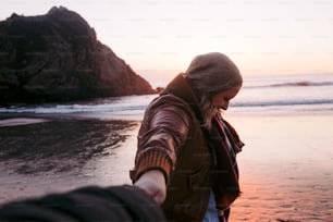 a person holding the hand of another person on a beach