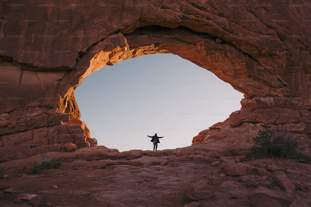 a person standing in a cave with their arms outstretched
