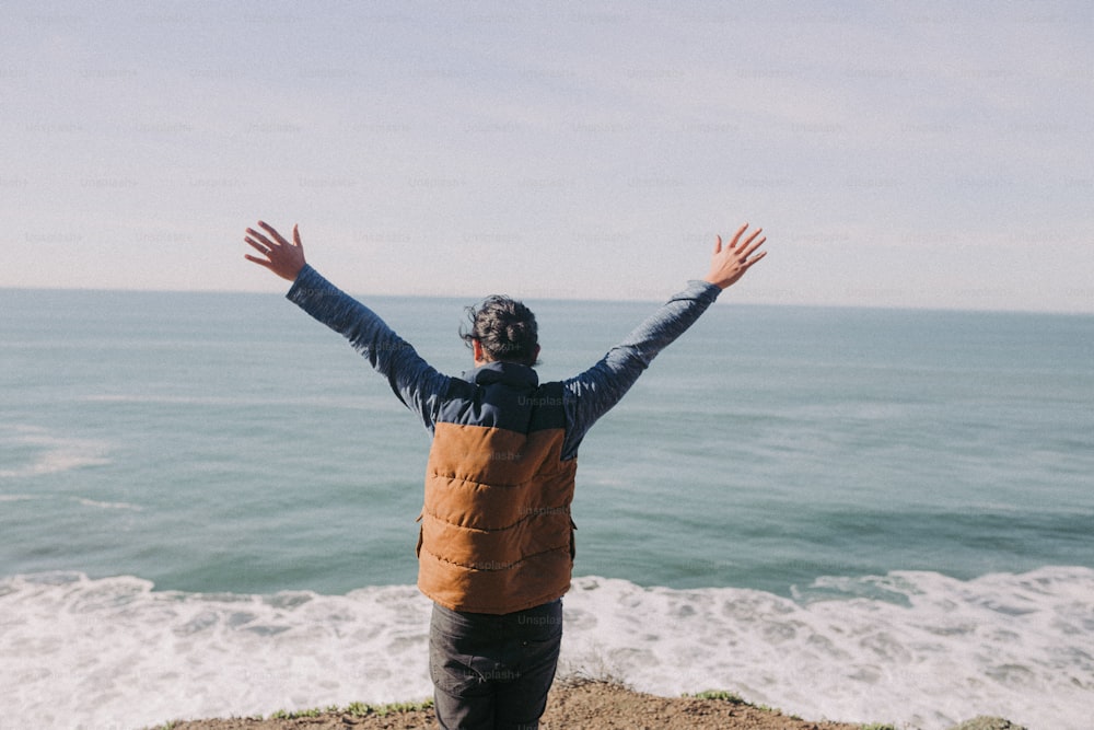 a man standing on top of a beach next to the ocean