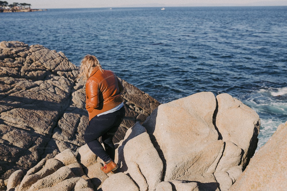 Una mujer sentada en una roca cerca del océano