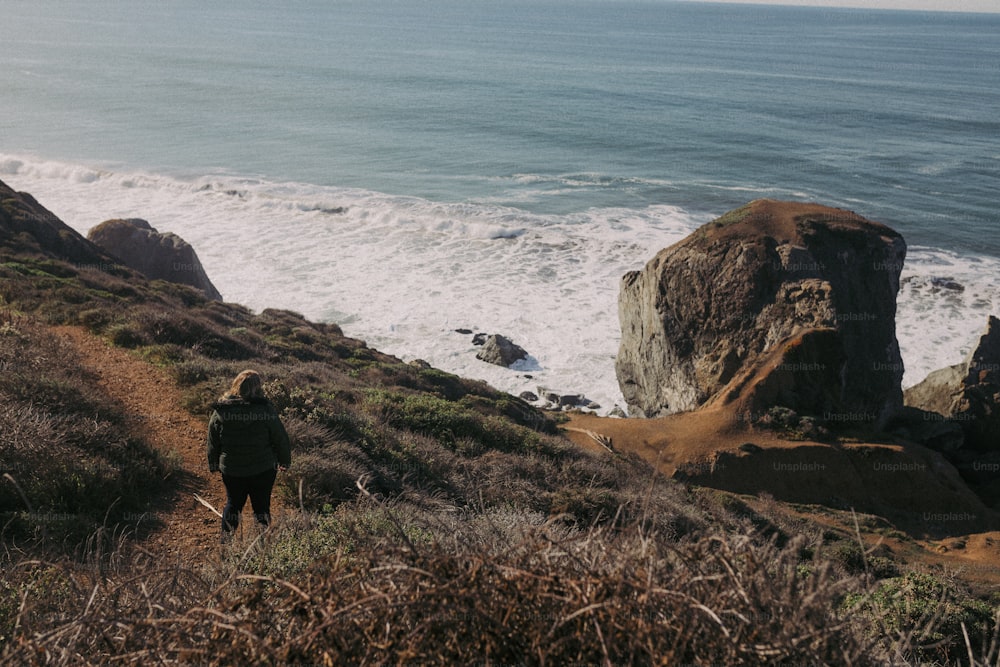 Una persona che cammina su una collina vicino all'oceano