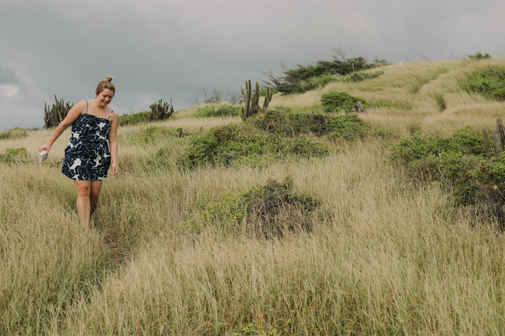 Una mujer con un vestido caminando a través de la hierba alta