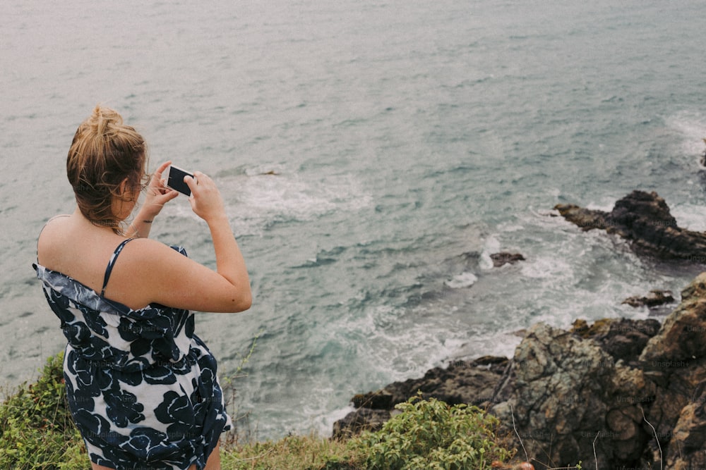a woman taking a picture of the ocean
