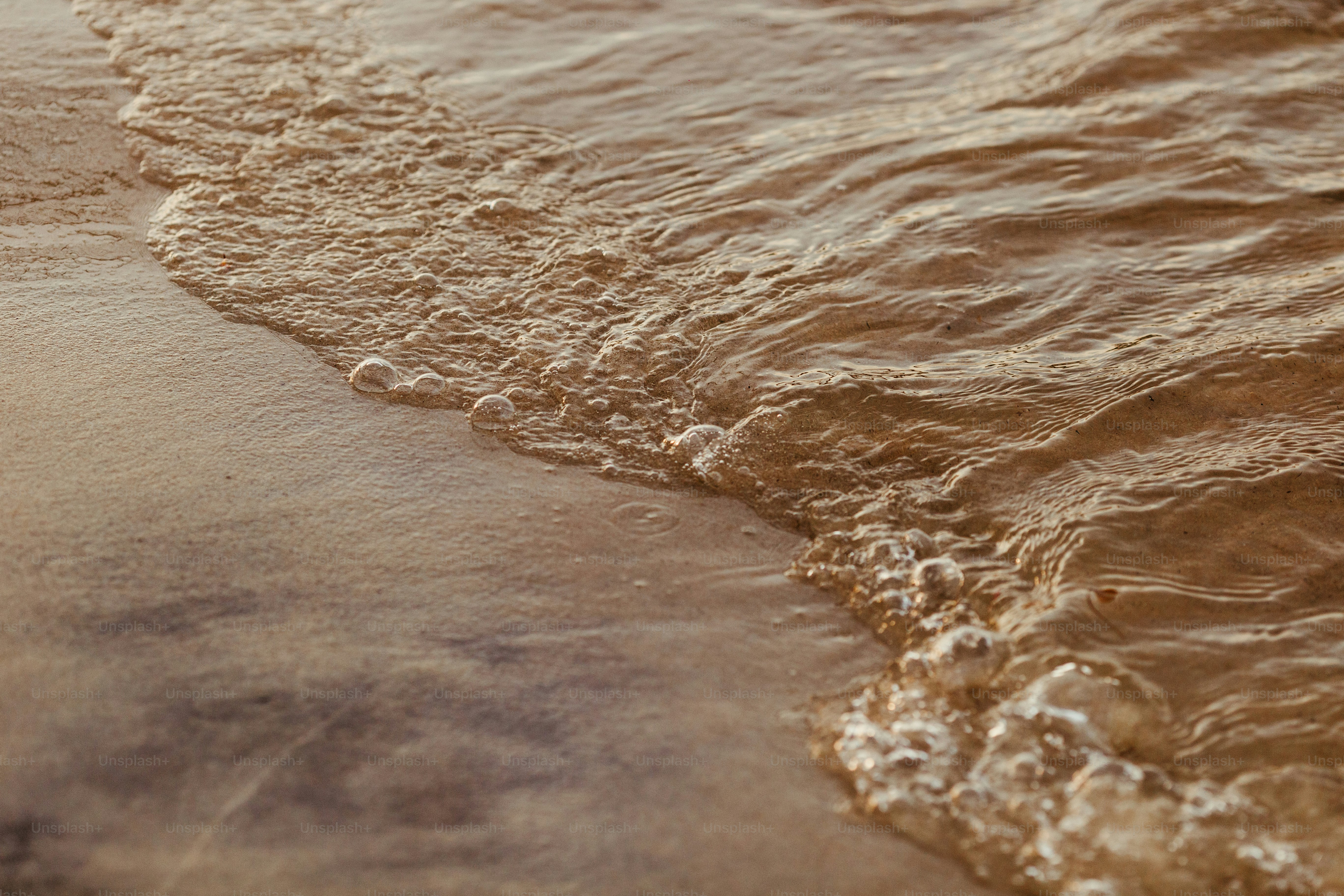 a close up of a beach with waves coming in