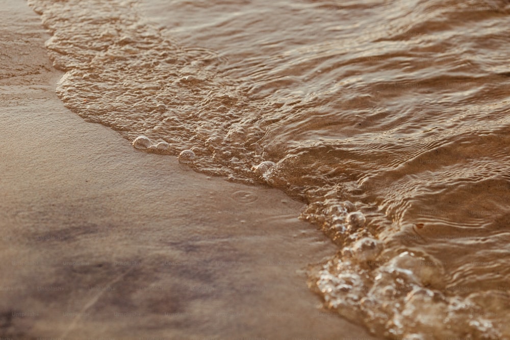 a close up of a beach with waves coming in