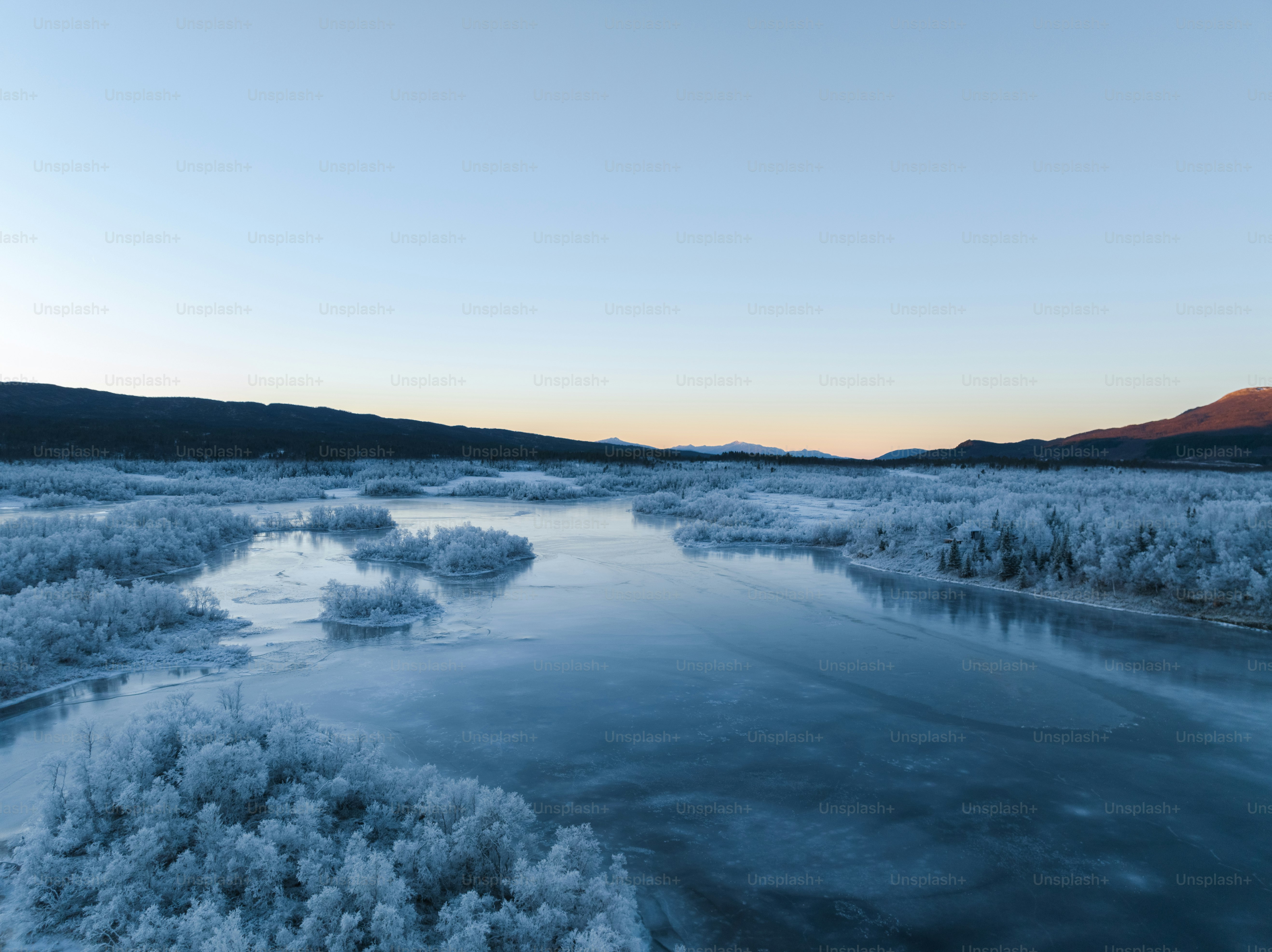An aerial view of a river surrounded by snow photo – Trees Image on ...