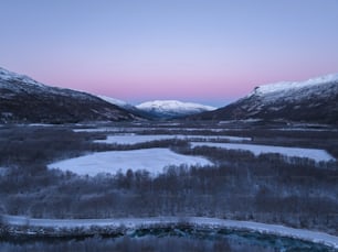 a snowy landscape with mountains in the background