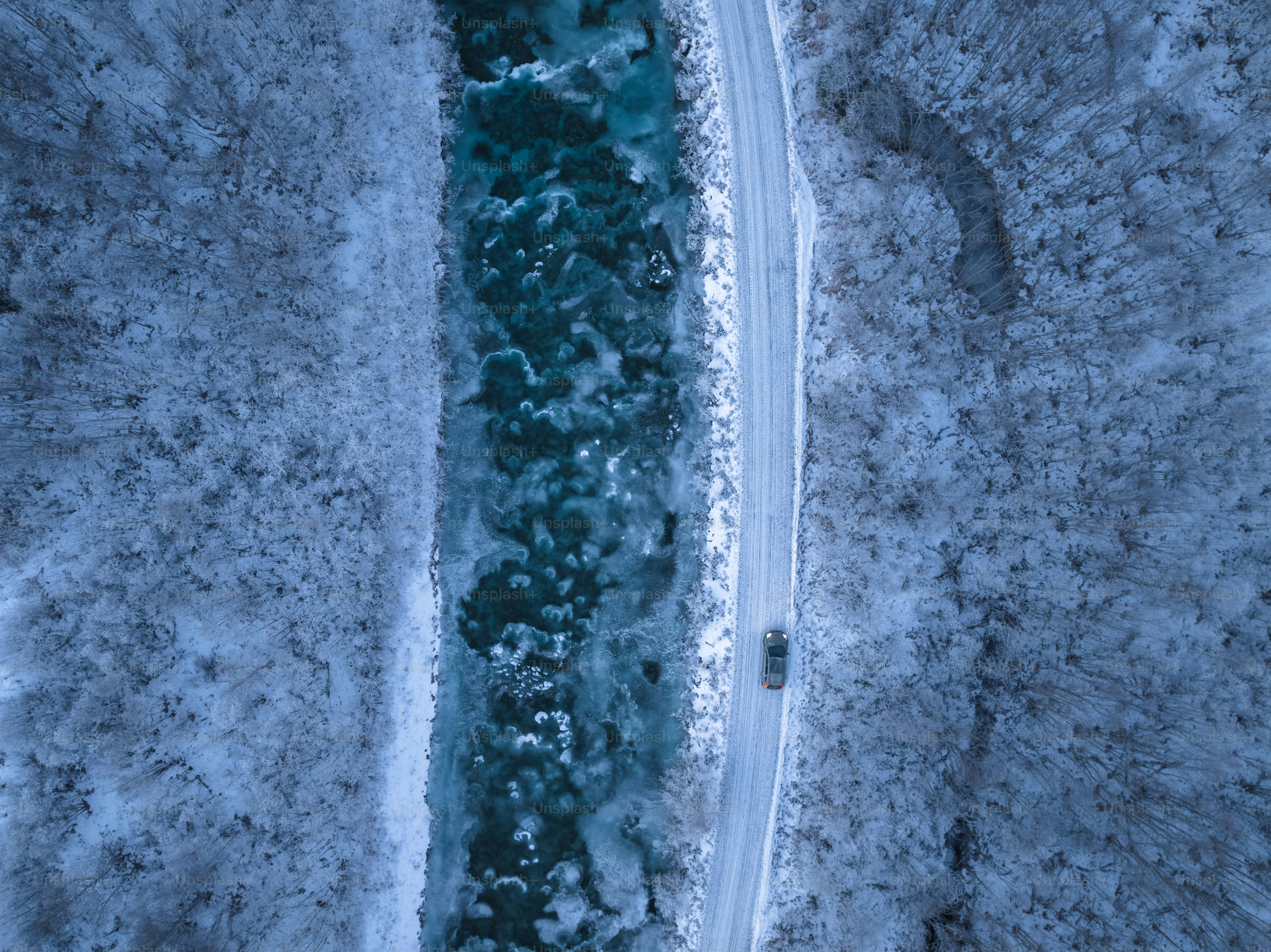 An aerial view of a river surrounded by snow photo – Trees Image on ...