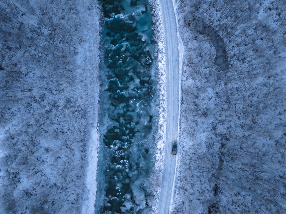 an aerial view of a car driving on a snowy road