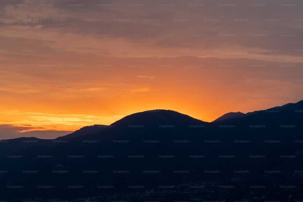 the sun is setting over a mountain range