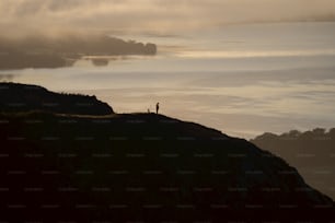 a person standing on a hill overlooking a body of water