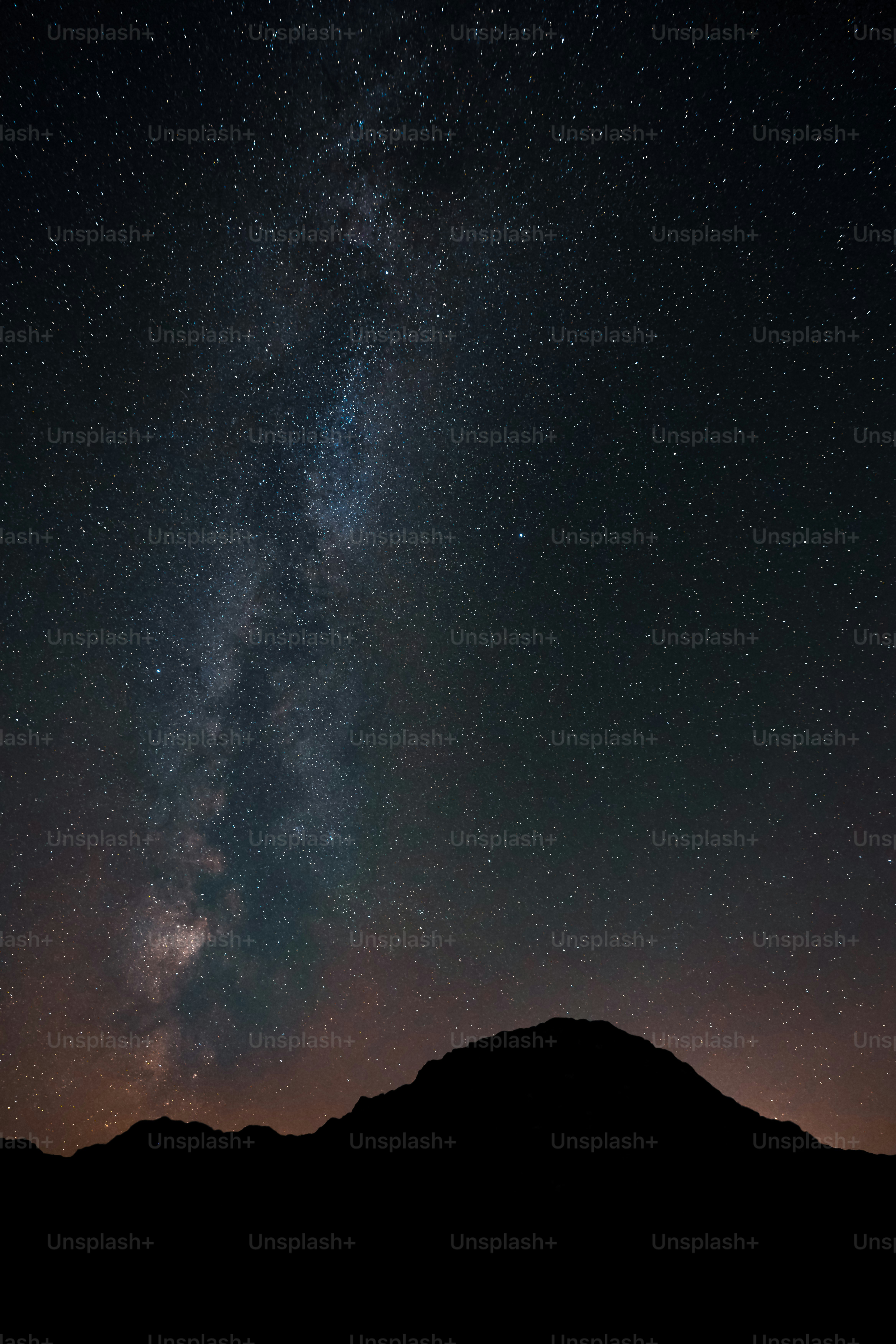 the night sky with stars above a mountain