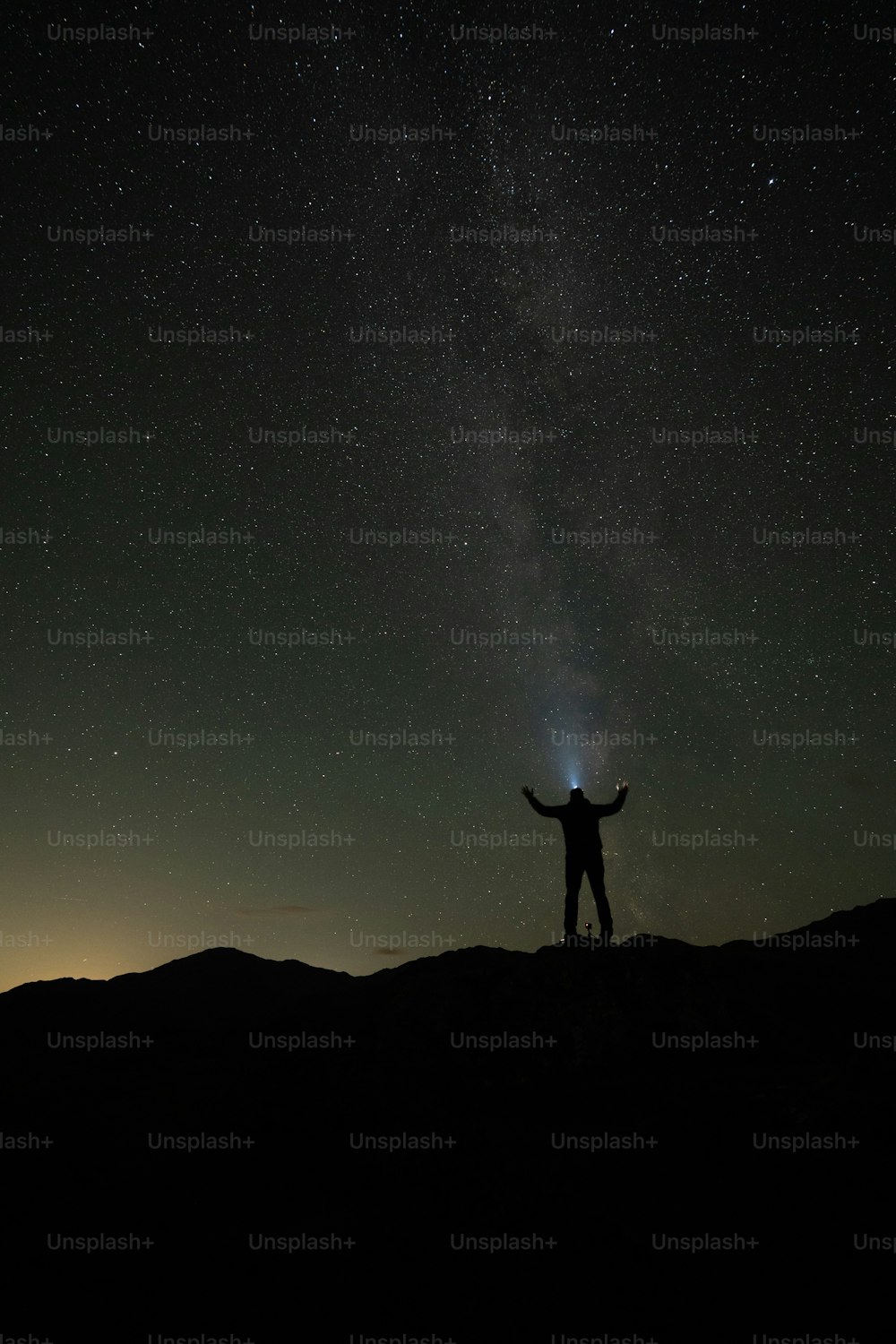 a man standing on top of a hill under a night sky