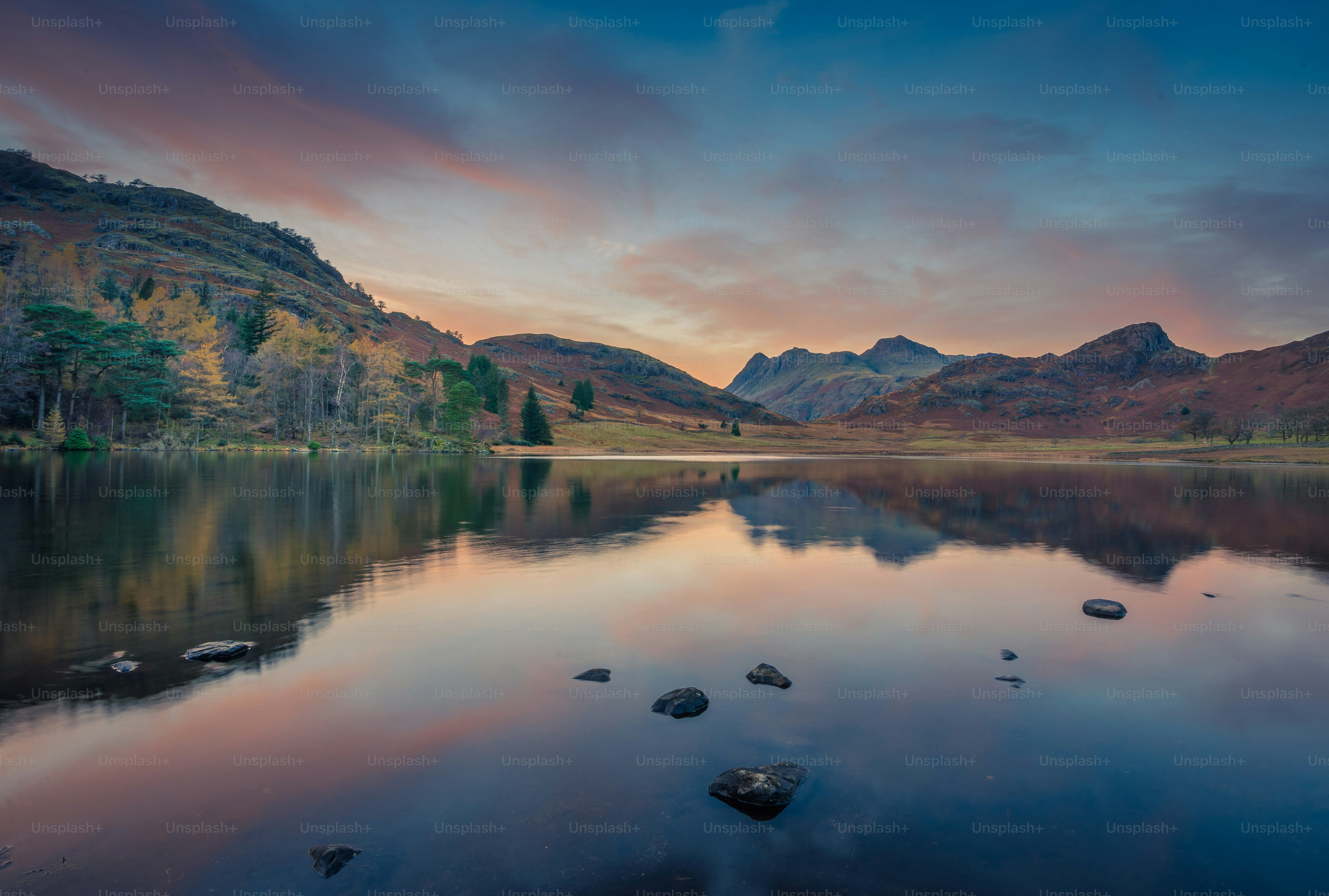 a lake surrounded by mountains under a cloudy sky