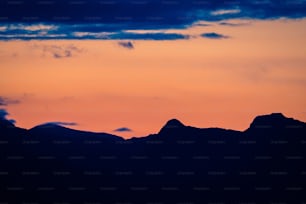 Ein Flugzeug, das bei Sonnenuntergang über eine Bergkette fliegt