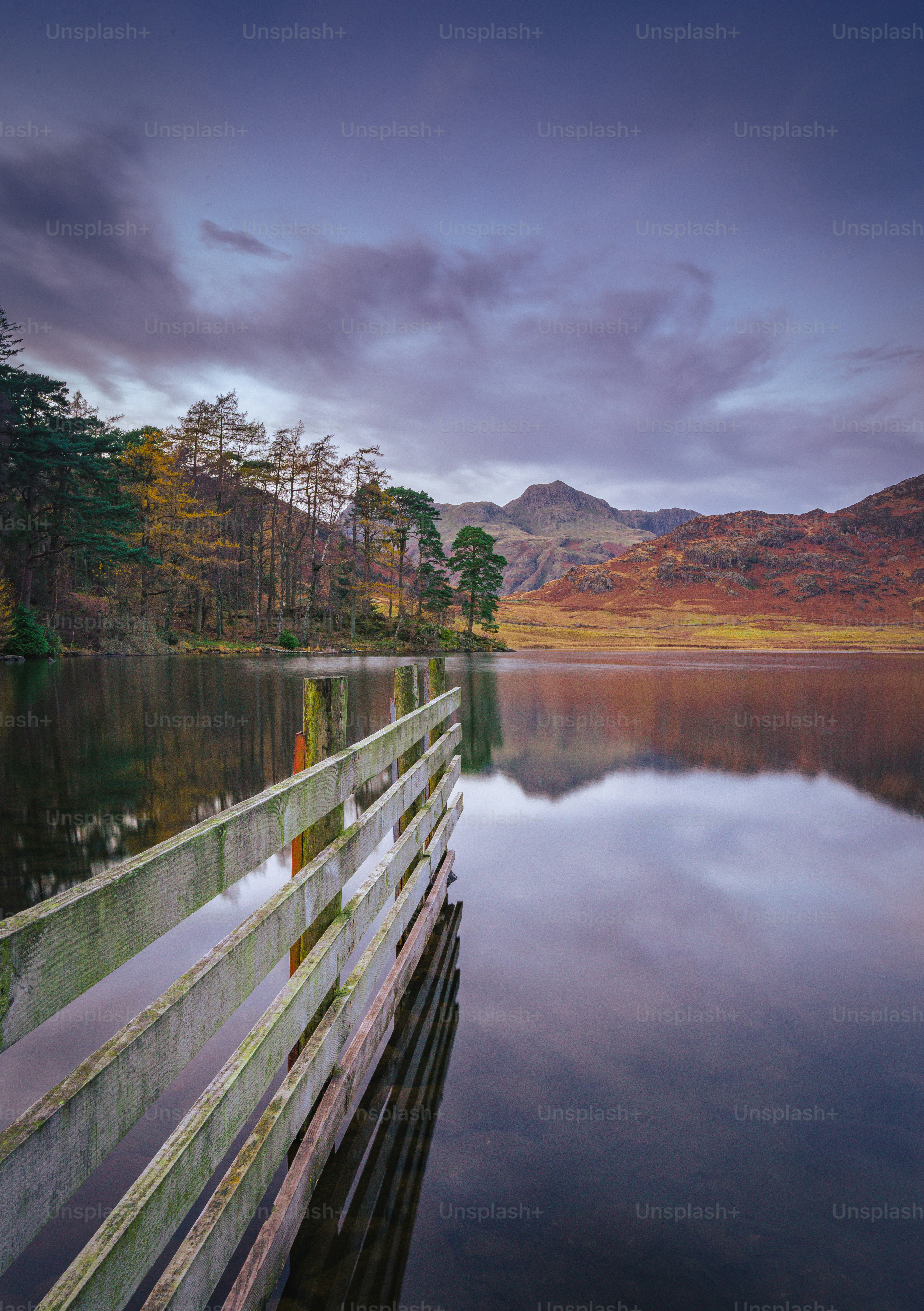 a wooden dock sitting on top of a lake under a cloudy sky