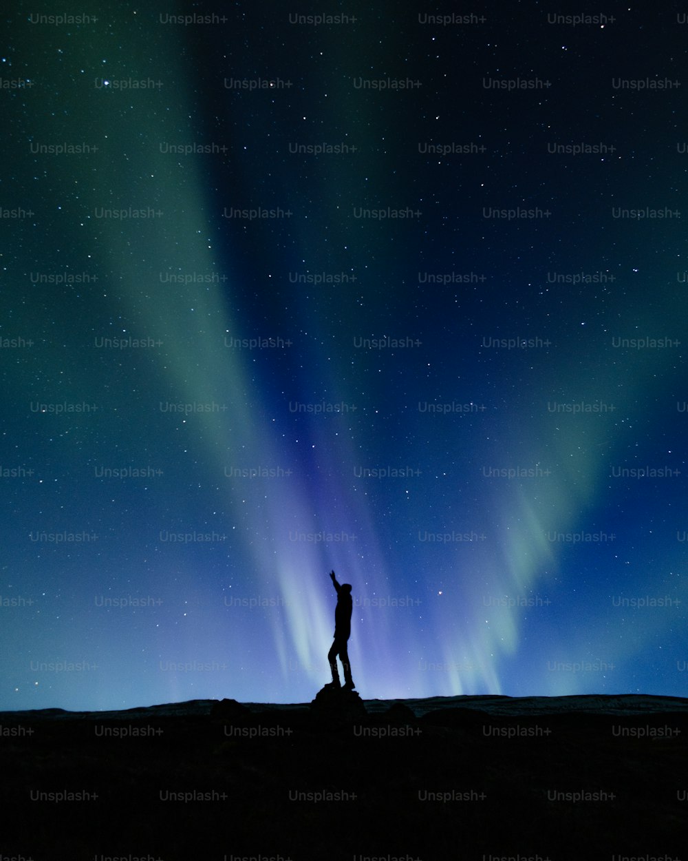 Un uomo in piedi sulla cima di una collina sotto un cielo pieno di stelle