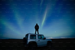 Un homme debout sur le toit d’une voiture sous le ciel nocturne