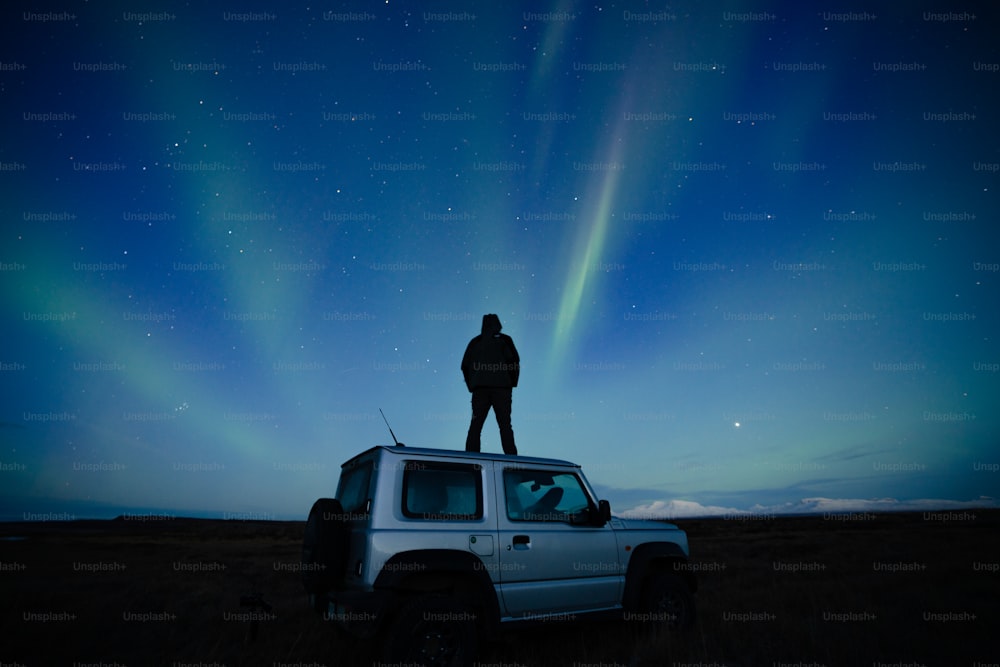 a man standing on top of a car under the night sky