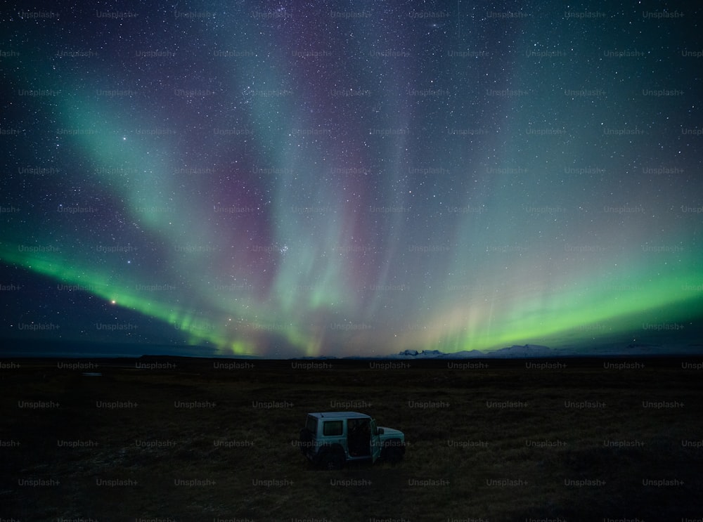 Un camion est stationné dans un champ sous les aurores boréales