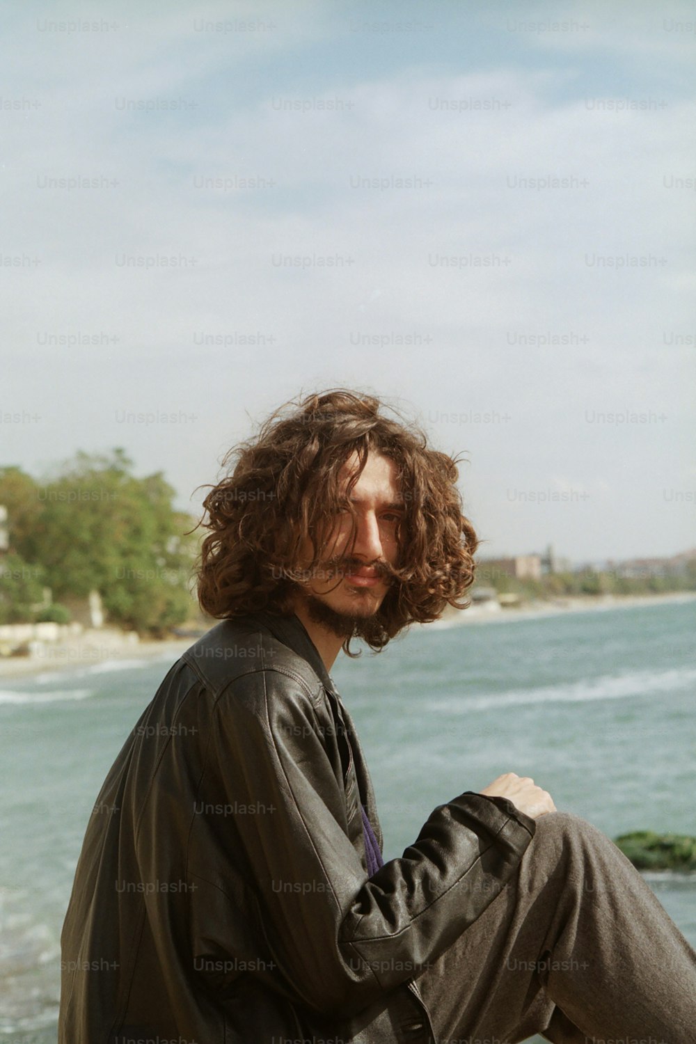 a man sitting on a rock near the ocean